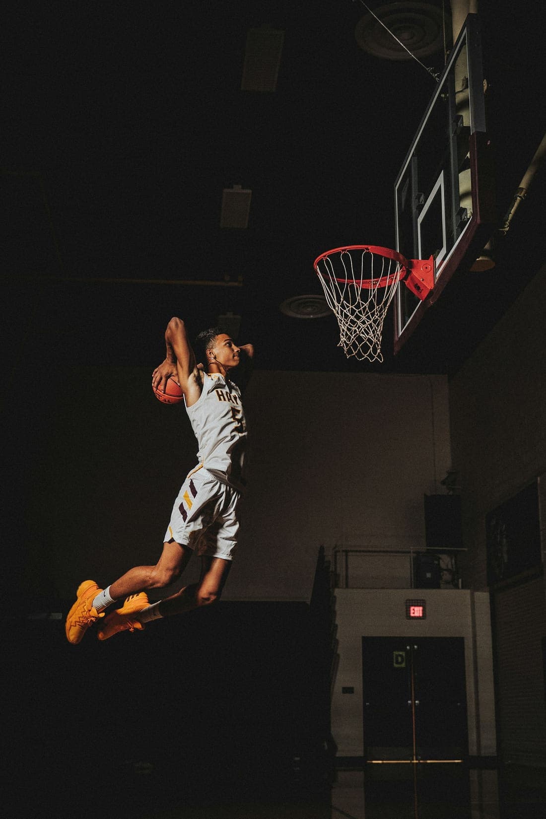 A basketball player going up for a dunk in a dark gym