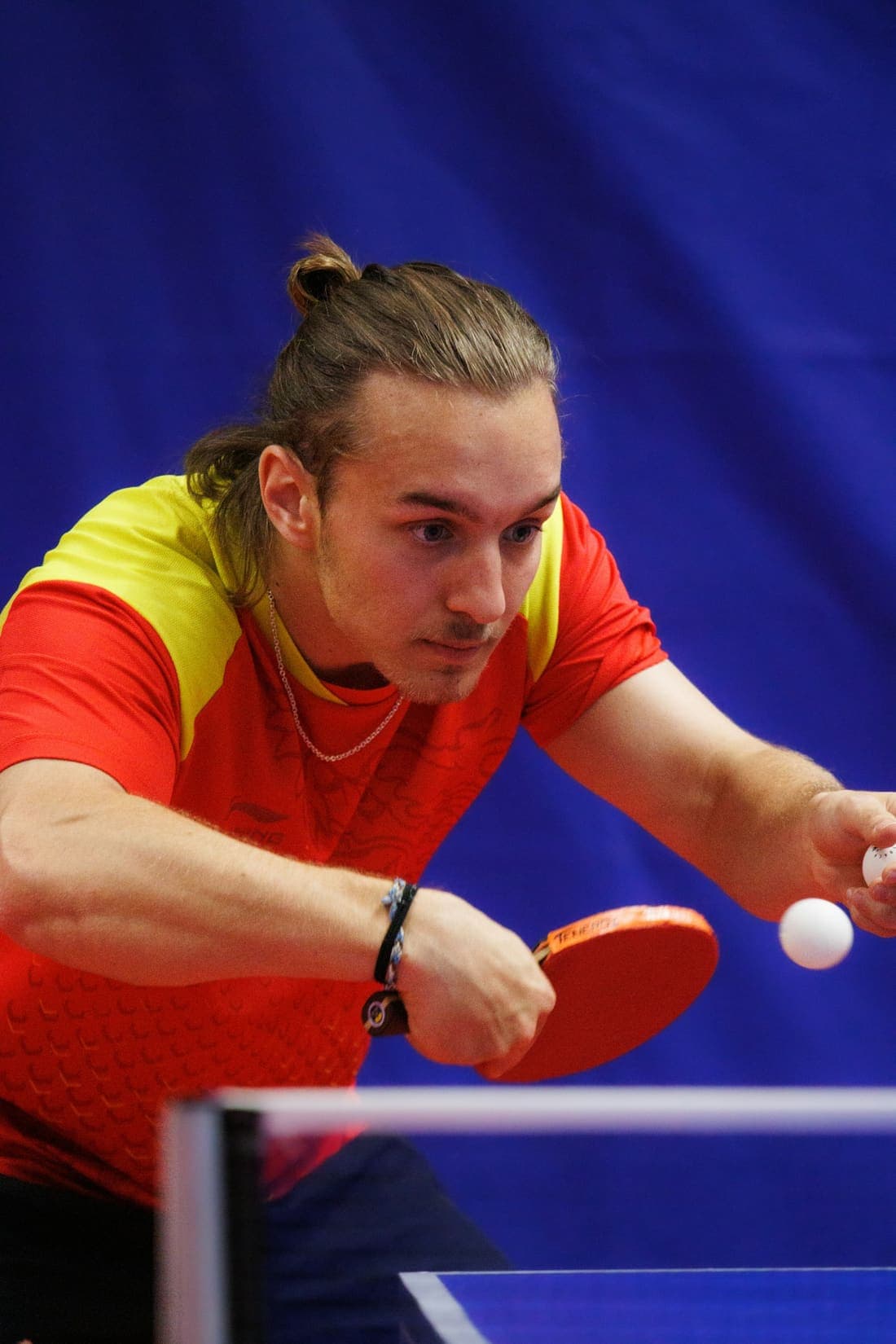 A table tennis player leaning in to return the ball